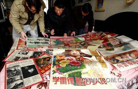 3月1日，房冠龍（中）在家中整理關(guān)于雷鋒的宣傳海報(bào)。